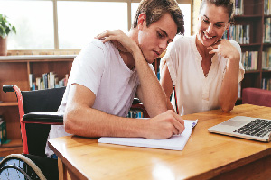 male student takes notes as a female instructor overlooks