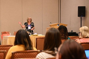 female presents from the front of a room with audience members visible in the foreground