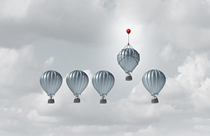 group of silver got air balloons floating in a cloudy sky with one floating above the rest