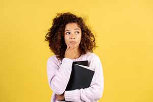 yellow background with a female wearing a pink sweater looking inquisitively off to the side