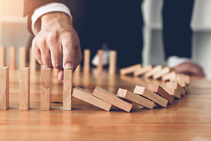 Photograph of individual preventing dominoes from falling.