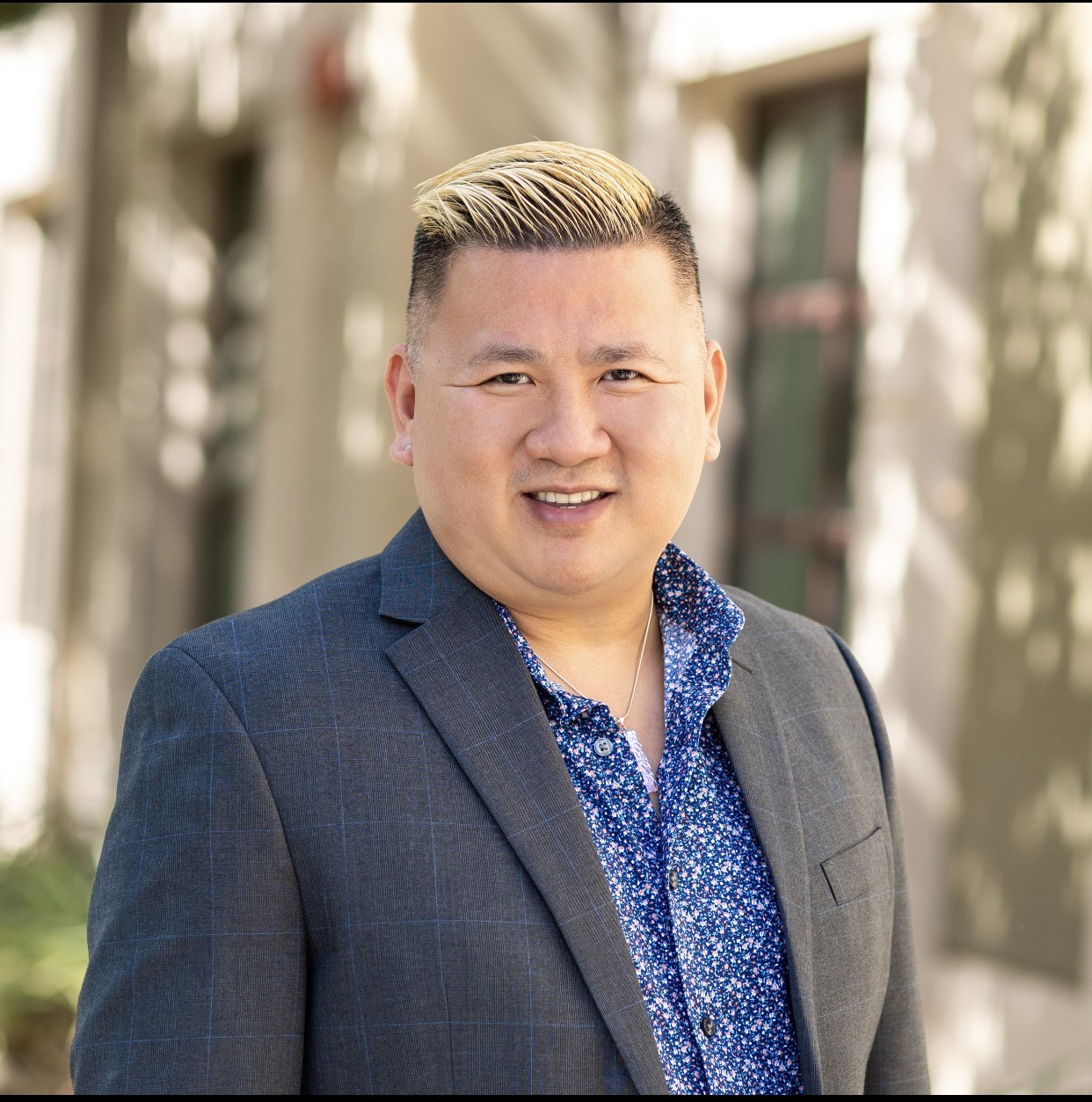Vinh in dark grey suit with blue floral pattern shirt