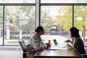 Two people sitting across from each other at a desk looking at a computer